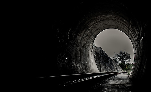 在铁路隧道和铁路内部 尽头有自然光 隧道尽头的光 光与影 实现目标的概念入口建筑学岩石阳光风景希望轨道黑色石头黑暗背景