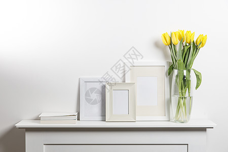 装在玻璃花瓶中的黄色郁金香和带有白色抽屉柜内刻字空间的照片框图片