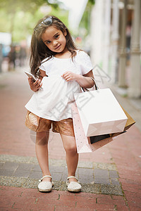 下一步我们应该去哪里购物 一个可爱的小女孩在城里外出时提着购物袋的画像背景