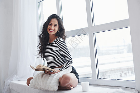 微笑着寻找肖像 女孩坐在窗台上看书 享受免费的一天图片