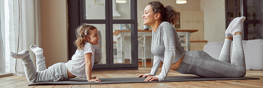 一起做瑜伽幸福的母亲在家和女儿一起漫步 做快乐的母亲灵活性家庭低角度身体训练女性活动孩子停留微笑背景
