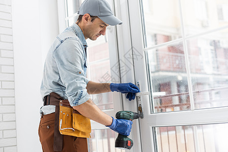 建筑工人在房屋中安装窗户 杂工用螺丝起子把窗户修好修理工维修建设者工作房子男性安全钻孔男人电气图片