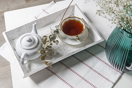 室内和家庭舒适的概念 顶视图 一杯茶 一壶凉茶 桌上白色木制托盘上的糖碗 瓷杯图片
