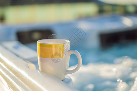 热水浴缸水力按摩池边的杯子 早上喝一杯 照明池 在城外休息 带水力按摩池的小屋水池服务乐趣陶瓷管子制品洗澡草本植物塑料假期图片