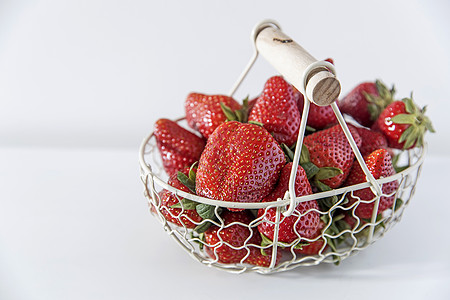 白金属篮子 配有木制手柄和米色桌上新鲜草莓甜点水果维生素场地绿色农业食物浆果农场收成图片