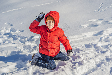 穿着蓝色冬装的滑稽小男孩在降雪期间行走 孩子们的户外冬季活动 可爱的孩子戴着一顶温暖的帽子 低低地遮住眼睛 用舌头捕捉雪花图片