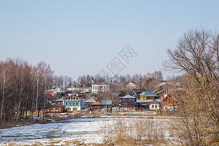 一小条冷冻的河 背景中的农村住房 春天 雪融化图片