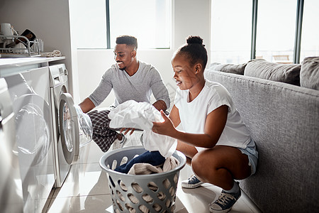 劳动分工不仅仅是工作场所的 是一对快乐的年轻夫妇在家一起洗衣服的镜头 (笑声)背景图片