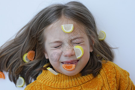 一个小女孩的肖像 与糖果躺在地板上 和毛发在黄色毛衣中孩子喜悦甜蜜甜点卷曲说谎饮食食物女孩女性图片