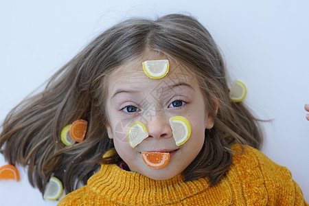 一个小女孩的肖像 与糖果躺在地板上 和毛发在黄色毛衣中喜悦甜蜜食物说谎女孩孩子卷曲饮食甜点女性图片