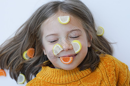一个小女孩的肖像 与糖果躺在地板上 和毛发在黄色毛衣中卷曲食物说谎女性喜悦甜点甜蜜饮食女孩孩子图片