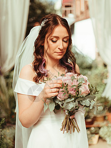 穿着新娘的裙子站在绿色花园里 拿着一束盛满鲜花和绿麦效应的婚礼花束夫妻装饰风格牡丹女性玫瑰乡村庆典花园婚姻图片