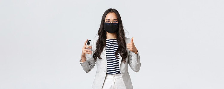 商业 金融和就业 covid19 预防病毒和社会疏远概念 戴着面罩的微笑女商务人士展示洗手液和竖起大拇指 要求使用它工作办公室企图片