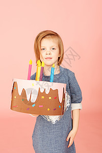 一个兴奋的漂亮小女孩的肖像 庆祝生日和展示蛋糕 在粉红背景上显示饼图片