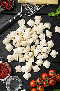 意大利拉维奥利配有新鲜的里科塔叶和西红柿 黑色木制桌边背景图片