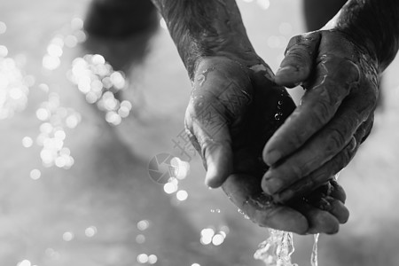 男人将水滴从一只手传递到另一只手 握住在张开的手掌上舀出液体 特写照片 男性强壮手臂中的真实自然之美 清澈海水 保存纯净水源 保图片