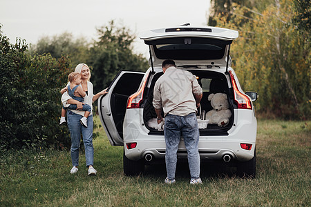 两位父母带着他们的小孩准备在户外野餐 年轻的家庭在 SUV 车上享受公路旅行图片