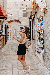 在一个美丽的夏日 在黑山布德瓦老城区的地中海中世纪城市 女游客穿过古老的狭窄街道 年轻美丽开朗的女人走在热带小镇的老街上 漂亮的图片