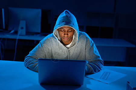 黑客们不会在压力下破解的 一个年轻的男性黑客在黑暗中破解了电脑密码背景图片