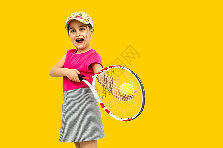 7岁女孩拍全长工作室照片 她拿着网球拍打和网球孤立橙色图片