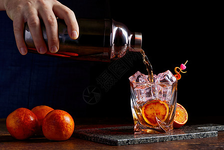 酒类鸡尾酒从摇摆者倒到无花果 石桌上有橙色皮冰柚子桌子摇床苏打芳香液体背景叶子玻璃庆典图片
