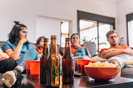 一张桌子的特写镜头 上面摆满了派对用的饮料和小吃 在客厅看足球的朋友图片