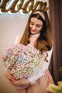 女人做春天的花束 女花店用包装纸捧着一束美丽的春花 满天星的美丽花组成女士高清图片素材