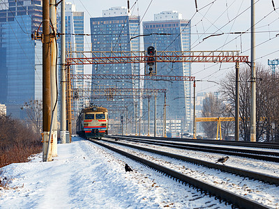 一辆旧电车在铁路上行驶 在阳光明媚的冬日摩天大楼的城市风景下图片