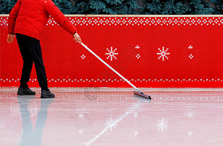 一名穿红色夹克的冰场工人用专用橡皮式冰拖把清洗冰块 复制空间图片