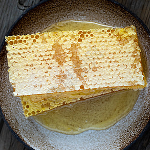蜂蜜中的蜂蜜 特写 白色陶瓷板 木制生锈的桌子液体食物蜜蜂营养香料乡村美食金子蜂窝木头图片