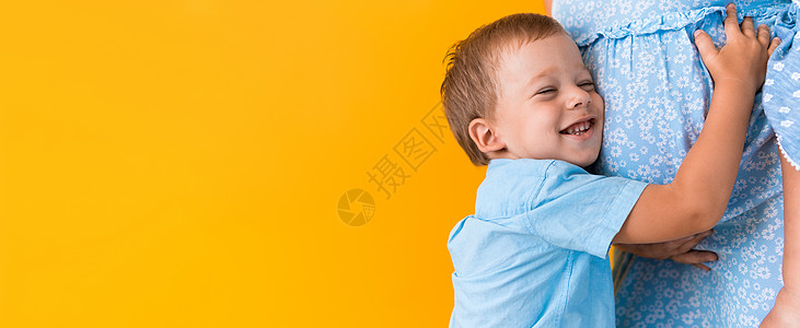 母性 女性气质 爱情 童年 炎热的夏天  剪下的横幅怀孕的面目全非的女人蓝色连衣裙小学龄前男孩的儿子兄弟姐妹拥抱黄色背景复制空间图片