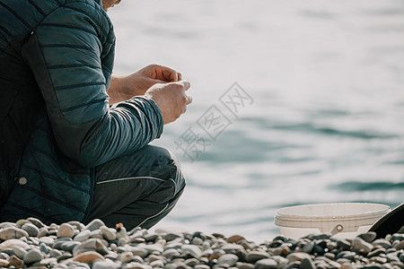 海上钓鱼的人爱好收紧鱼线卷轴 平静的海面 渔夫的特写镜头用手在鱼竿上扭动渔线轮 在户外的蓝色大海中钓鱼行动运动淡水金子消遣闲暇溪背景图片