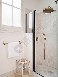 配有淋浴区 窗户 毛巾和木凳的旧米色洗手间图片