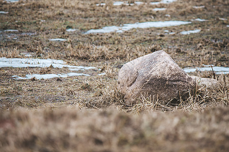 一片大石头在雪地之间的泥土地带上图片