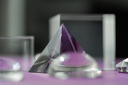 玻璃金字塔紫色背景的水晶棱镜折射光 魔法水晶和金字塔 球体和立方体 修行灵疗水晶 风水 良好的能量流概念背景风格橙子辉光太阳仪式装饰玻璃光背景