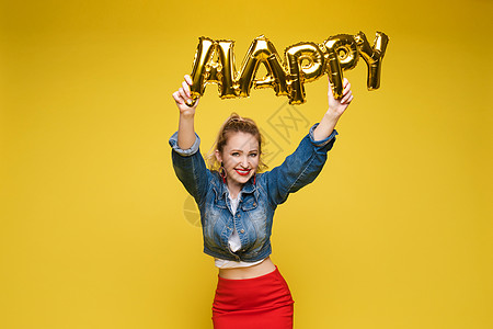 性格开朗的女孩 带着充气字母 HAPPY在橙色背景上隔离微笑橙子表情成人股票气球庆典幸福女士派对图片