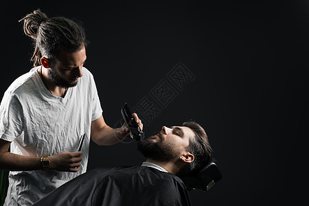 在理发店刮胡子 长着脚镣的理发师修剪英俊胡子的男人头发工作室男性剃刀店铺理发剃须顾客绅士主义图片