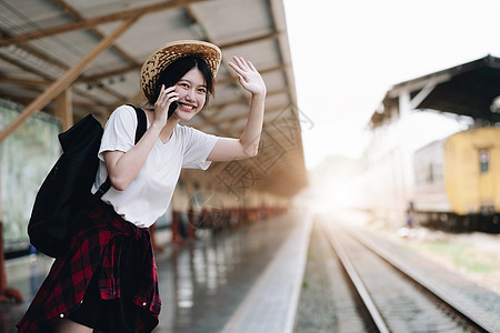 寻找朋友计划在火车站旅行的年轻旅行者妇女 夏天和旅行生活方式概念女性技术手机帽子车辆窗户商业眼镜游客车皮图片