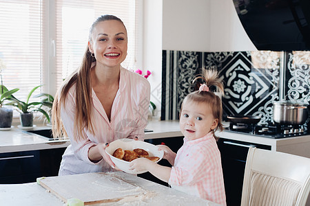 美丽的女人 可爱的孩子 拿着碗和饼干食谱女儿厨房女士享受女孩早餐家庭闲暇母亲图片