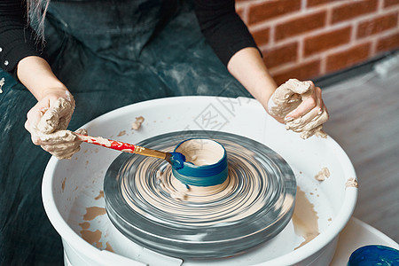 面目全非的女人在轮子上制作陶瓷陶器 涂成蓝色 自由职业者 商业女性的概念 手工艺品 赚外快 副业 把爱好变成现金图片