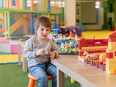 蹒跚学步的孩子在玩五颜六色的玩具积木 有玩具构造器图的小男孩 幼儿园或托儿所的内部 儿童室内休闲活动图片