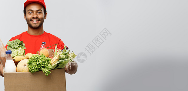 交付概念  英俊的非洲裔美国人送货员携带从商店运来的食品和饮料包箱 孤立在灰色工作室背景上 复制空间微笑面包杂货蔬菜顾客导游牛奶图片