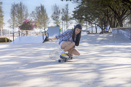年轻的亚洲女性早上在户外的公园滑板坡道上玩冲浪滑板 快乐的女人在公园玩滑板 体育活动生活方式概念乐趣街道极限女士溜冰者青年娱乐滚图片