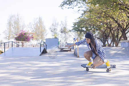 年轻的亚洲女性早上在户外的公园滑板坡道上玩冲浪滑板 快乐的女人在公园玩滑板 体育活动生活方式概念女士闲暇享受女孩滚筒极限森林娱乐图片