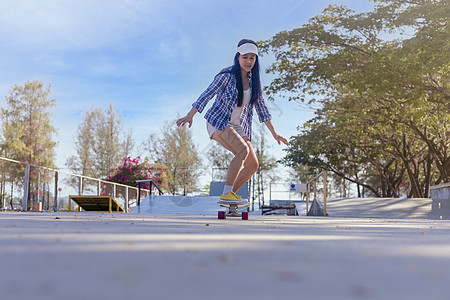 年轻的亚洲女性早上在户外的公园滑板坡道上玩冲浪滑板 快乐的女人在公园玩滑板 体育活动生活方式概念娱乐闲暇乐趣滑冰极限街道滚筒溜冰图片