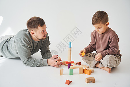 照顾爸爸和快乐的儿子玩耍 带着玩具木块在白色背景上 父亲和孩子的照料立方体活动童年男生家庭创造力产假喜悦建筑亲子图片