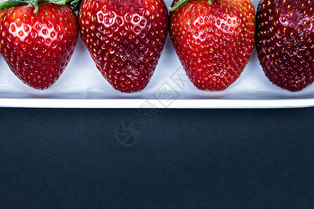 白色盘子里的草莓紧靠黑色背景 在白色碗的新鲜的红色草莓在黑背景 侧视图 复制空间 特写味道活力美食反射农场农业饮食食物甜点浆果图片