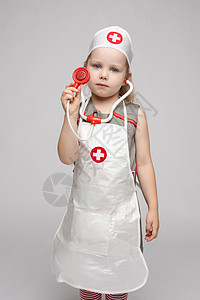 自信的小女孩穿着医生制服穿大衣 拿着听诊器 享受着玩耍图片