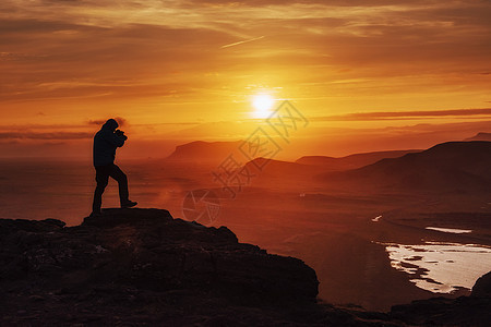 快乐的男人在日落时站在悬崖上风景游客天空摄影师旅行太阳摄影海鸥照片旅游图片