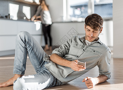 坐在厨房地板上有智能手机的年轻人邮件技术男人椅子学生电话生活网络互联网房子图片